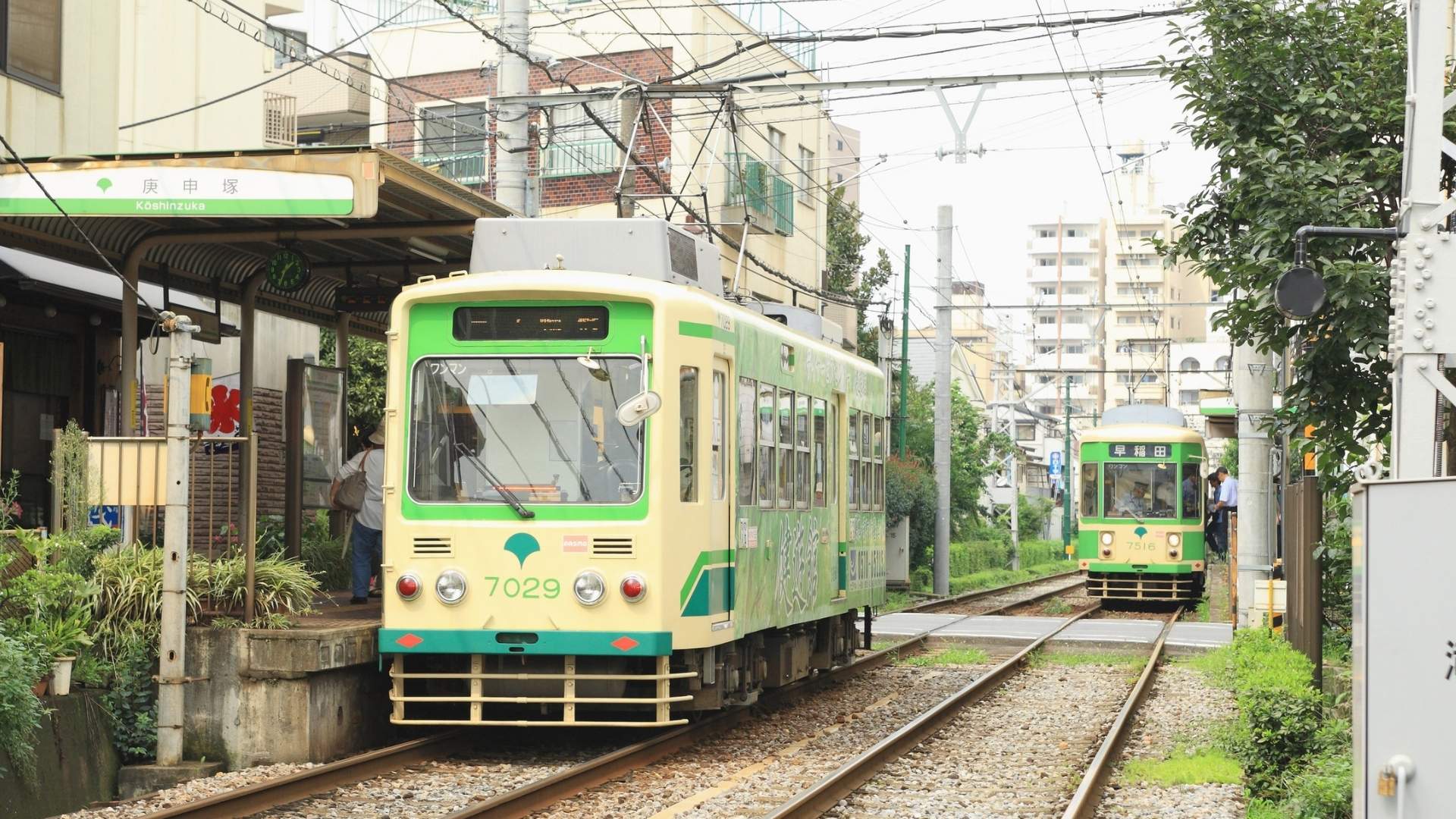 Tram Station in Japan with Two Green Trains