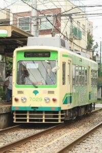 Tram Station in Japan with Two Green Trains
